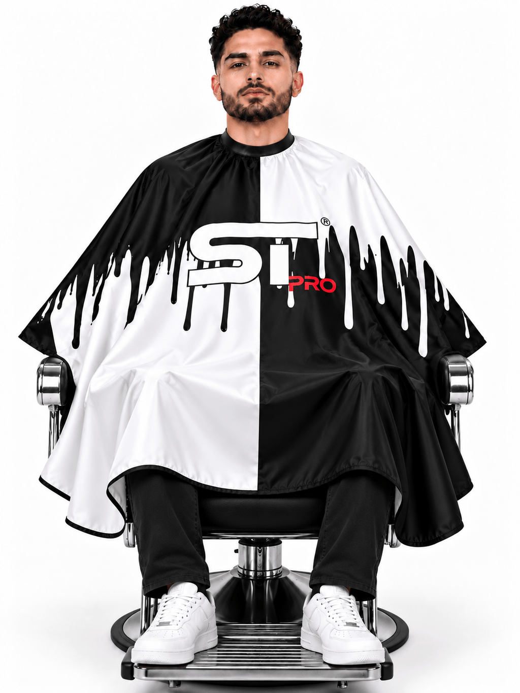 Seated client wearing a black-and-white split-design barber cape
