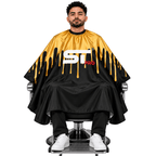 Seated client wearing a gold-and-black Supreme Trimmer barber cape